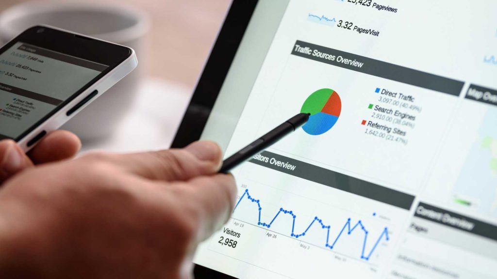 digital marketing concept hand holding phone while looking at marketing graph