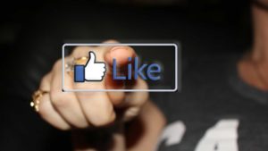 person pressing facebook like button on a touch screen 1