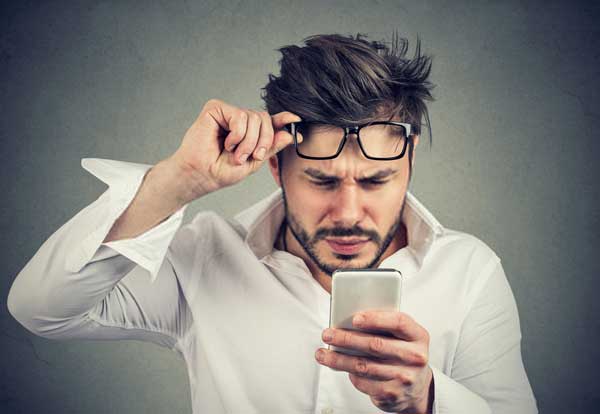 man with difficulty reading hard to read text on phone
