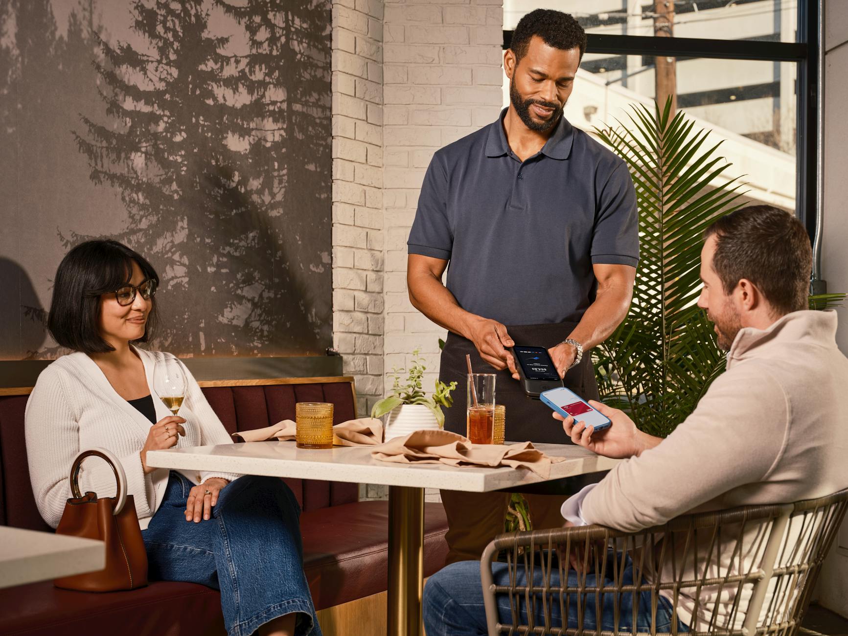 Customer using a mobile phone at a casual restaurant table with food and drink