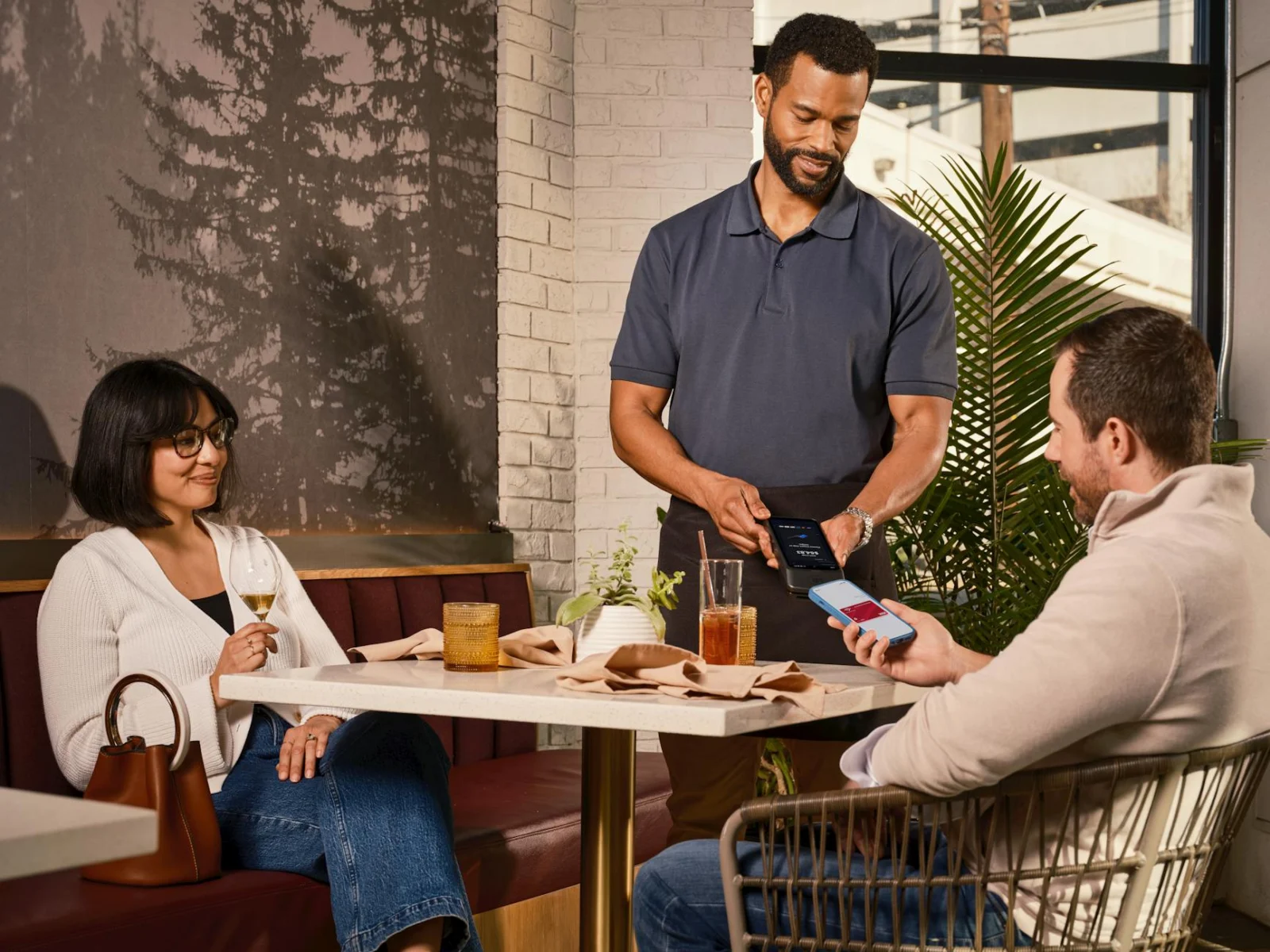 Customer using a mobile phone at a casual restaurant table with food and drink