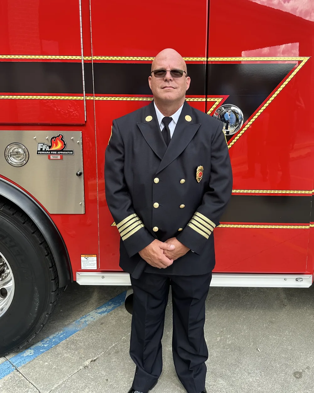 Clint Sanchez, owner of BlakSheep Creative, in Baton Rouge Fire Department dress uniform standing in front of a fire engine